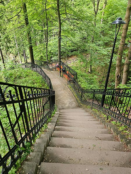 Strome schody z ozdobnymi, żeliwnymi balustradami prowadzące w głąb zalesionego wąwozu i punkty widokowe